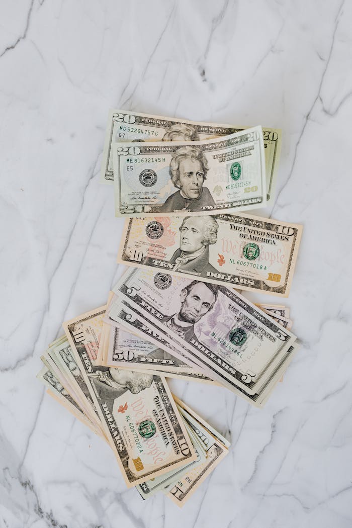 gallery-3 A collection of various US dollar bills laid out on a marble background.